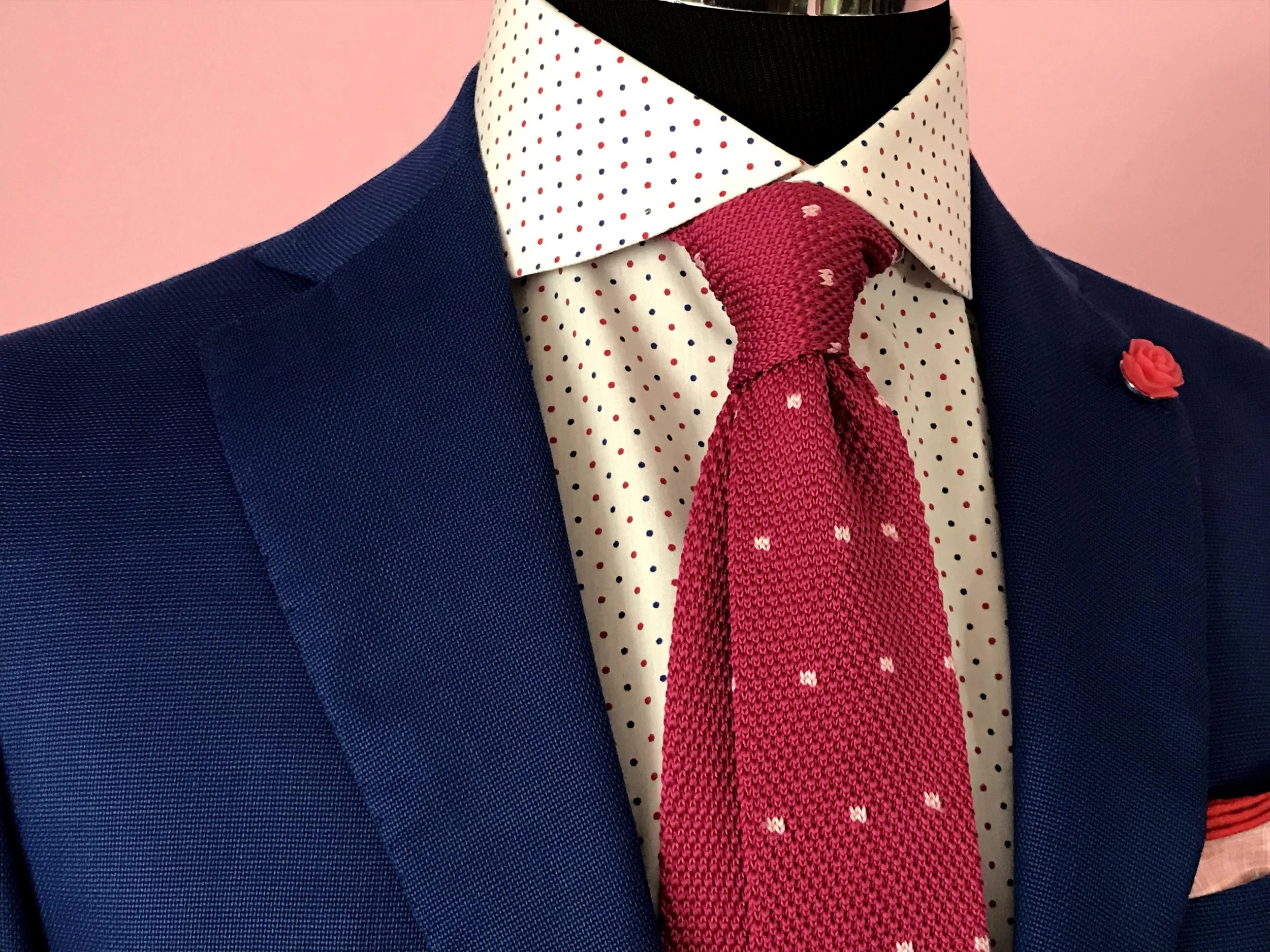 A navy jacket, polka-dot shirt, and red knit tie
